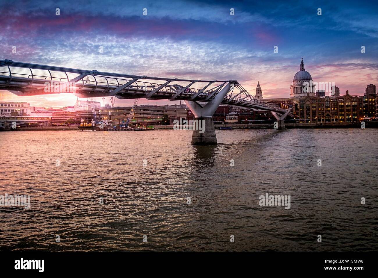 Millennium Bridge Over River Thames By St Pauls Cathedral Against Sky At Sunset Stock Photo