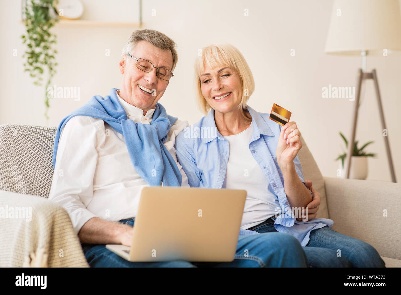 Excited older couple doing online shopping on laptop Stock Photo