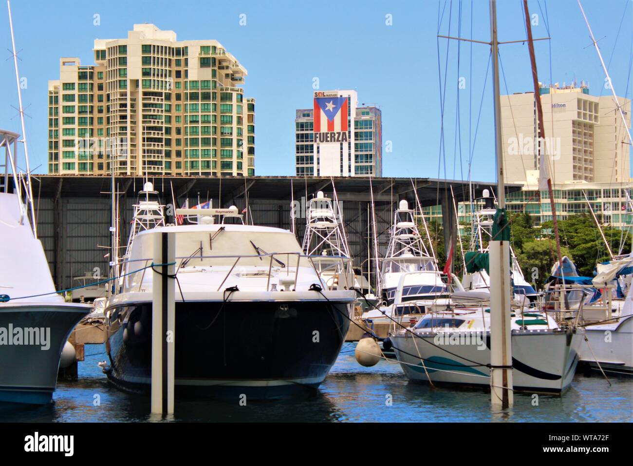 View from San Juan Bay Marina of moored boats in the foreground, and buildings in the background, including the headquarters of  'SOL Partners'. Stock Photo