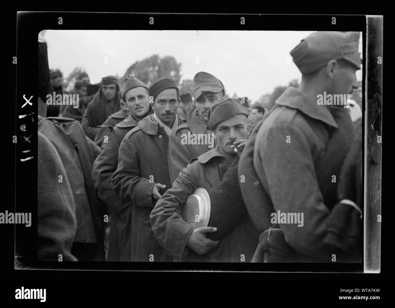 Men standing in line, one holding metal plate Stock Photo - Alamy