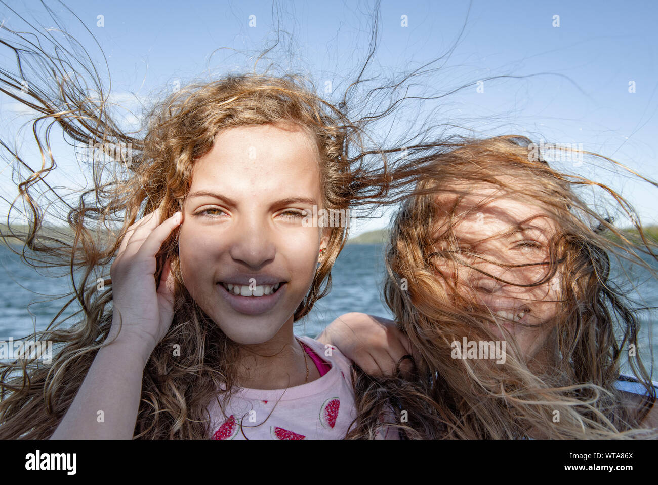 Disheveled hair twins smiling during strong gale Stock Photo