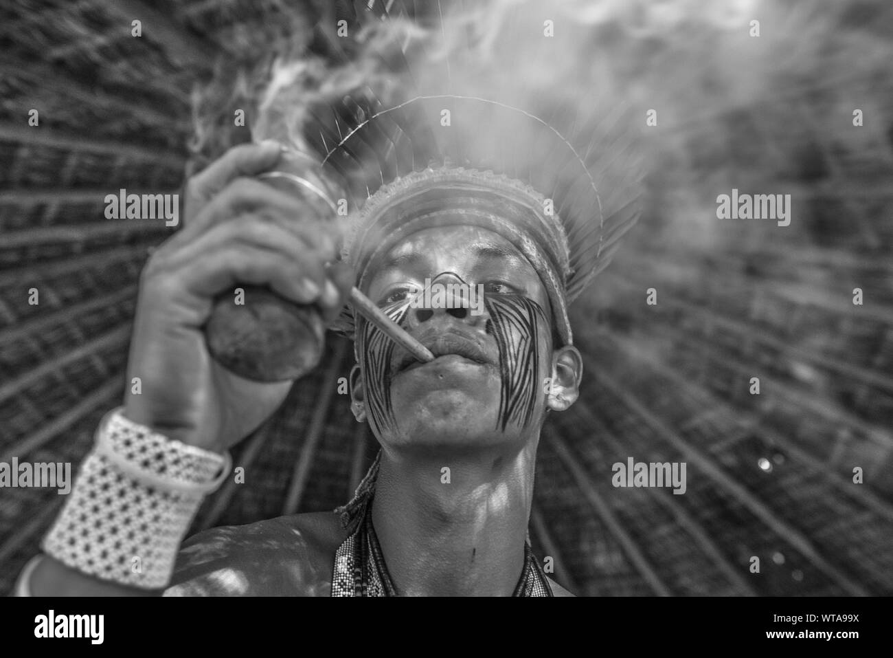 Brazilian Indian smokes traditional pipe at the village Stock Photo