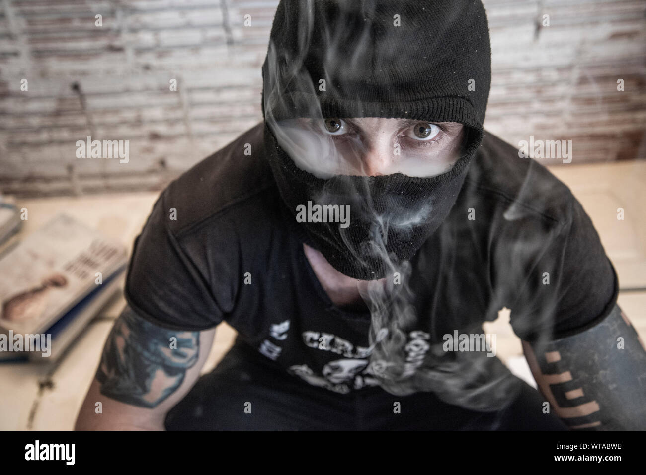 Anonymous punk activist smoking and wearing a balaclava Stock Photo