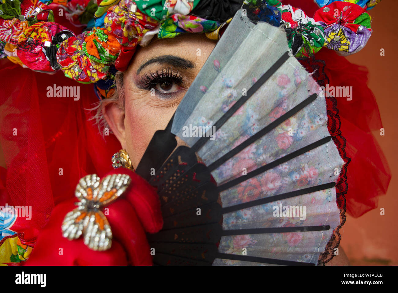 Drag Queen hiding face with oriental hand fan Stock Photo