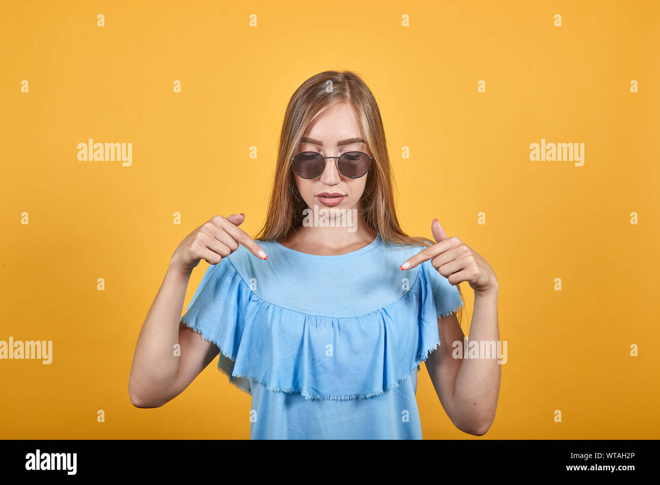 girl brunette in blue t-shirt over isolated orange background shows emotions Stock Photo