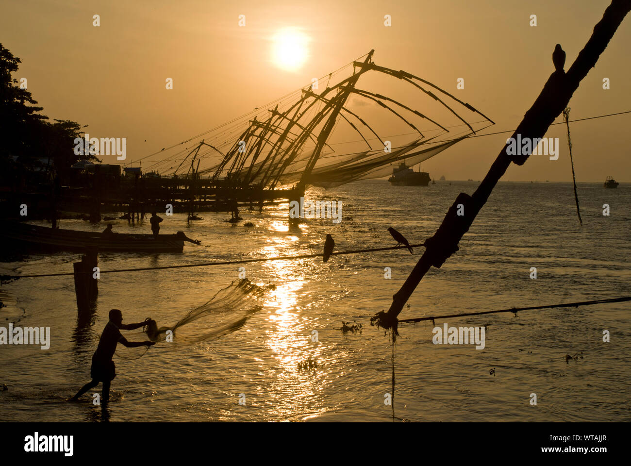 Fisherman works around the Chinese fishing nets of Fort Kochi Stock Photo