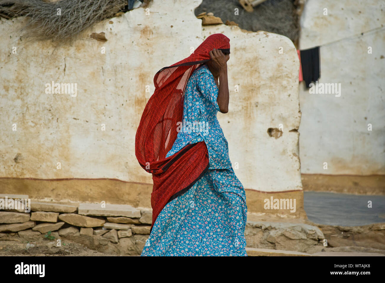 Traditional Rajastan woman walking in a typical village of Jaisalmer Stock Photo
