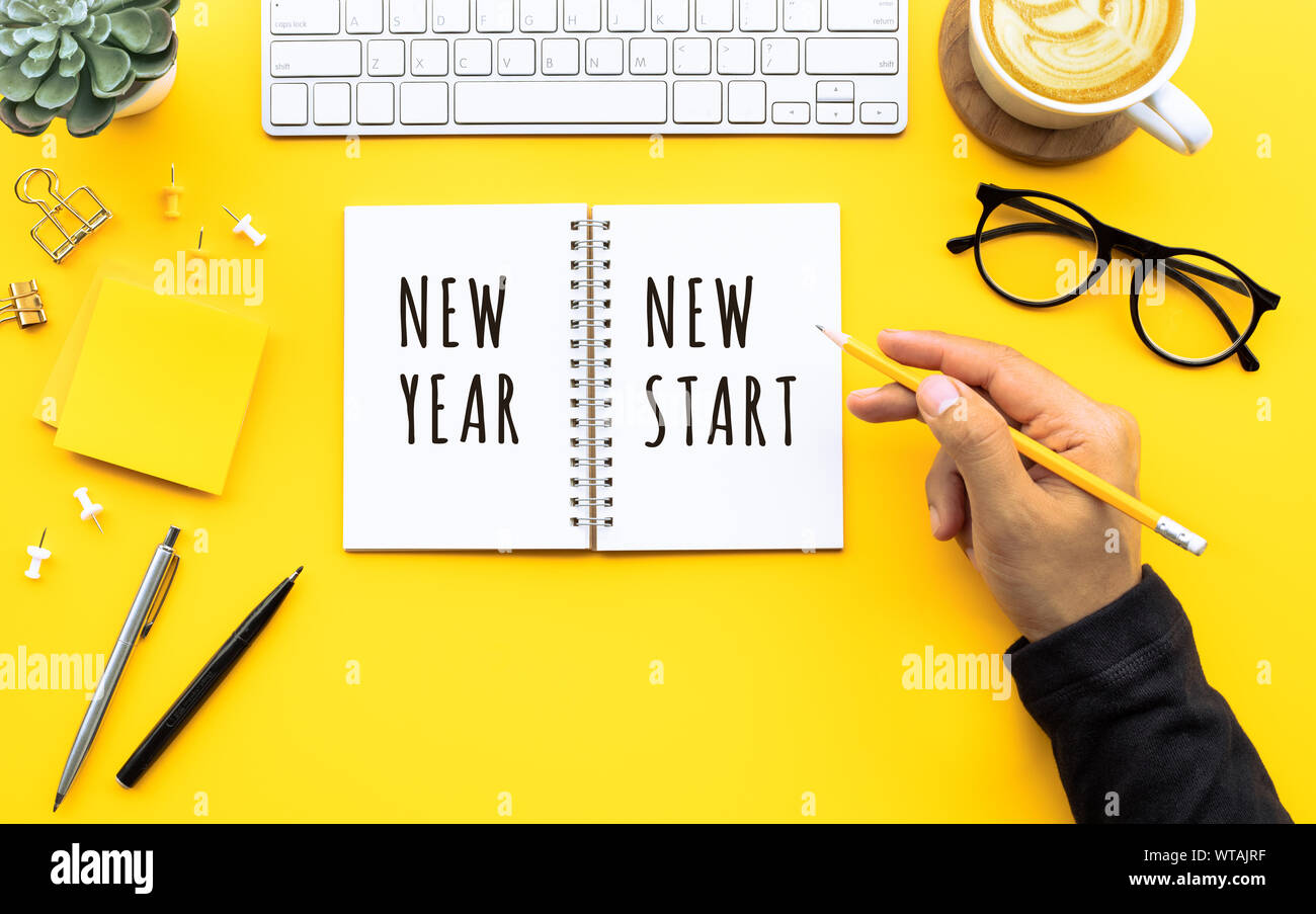 New year new start text with youngman writing on notepad on color desk table.Business goal-plan-action and resolution concepts ideas Stock Photo