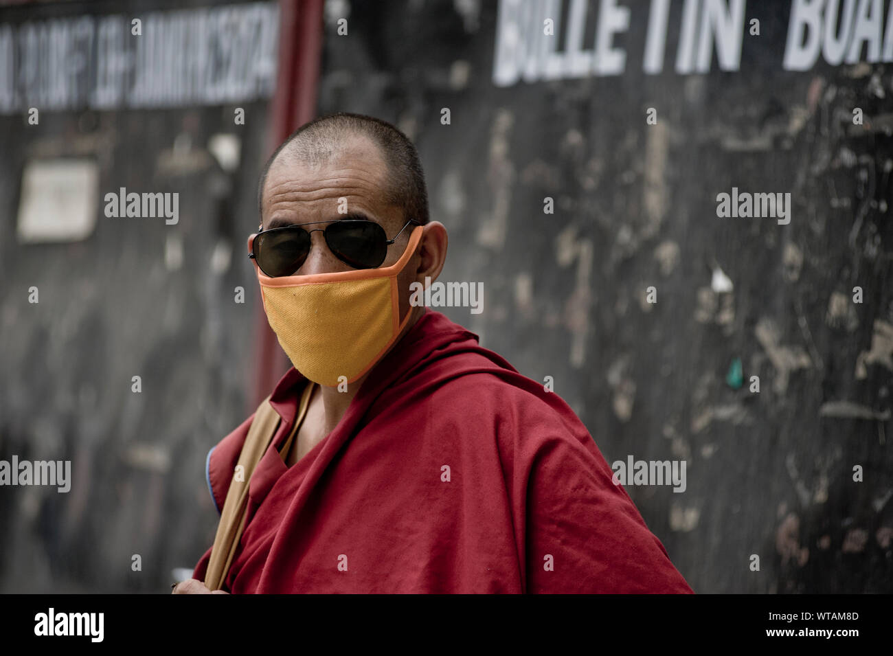 Monk in the streets of Leh wearing kasaya robe and anti-pollution mask Stock Photo