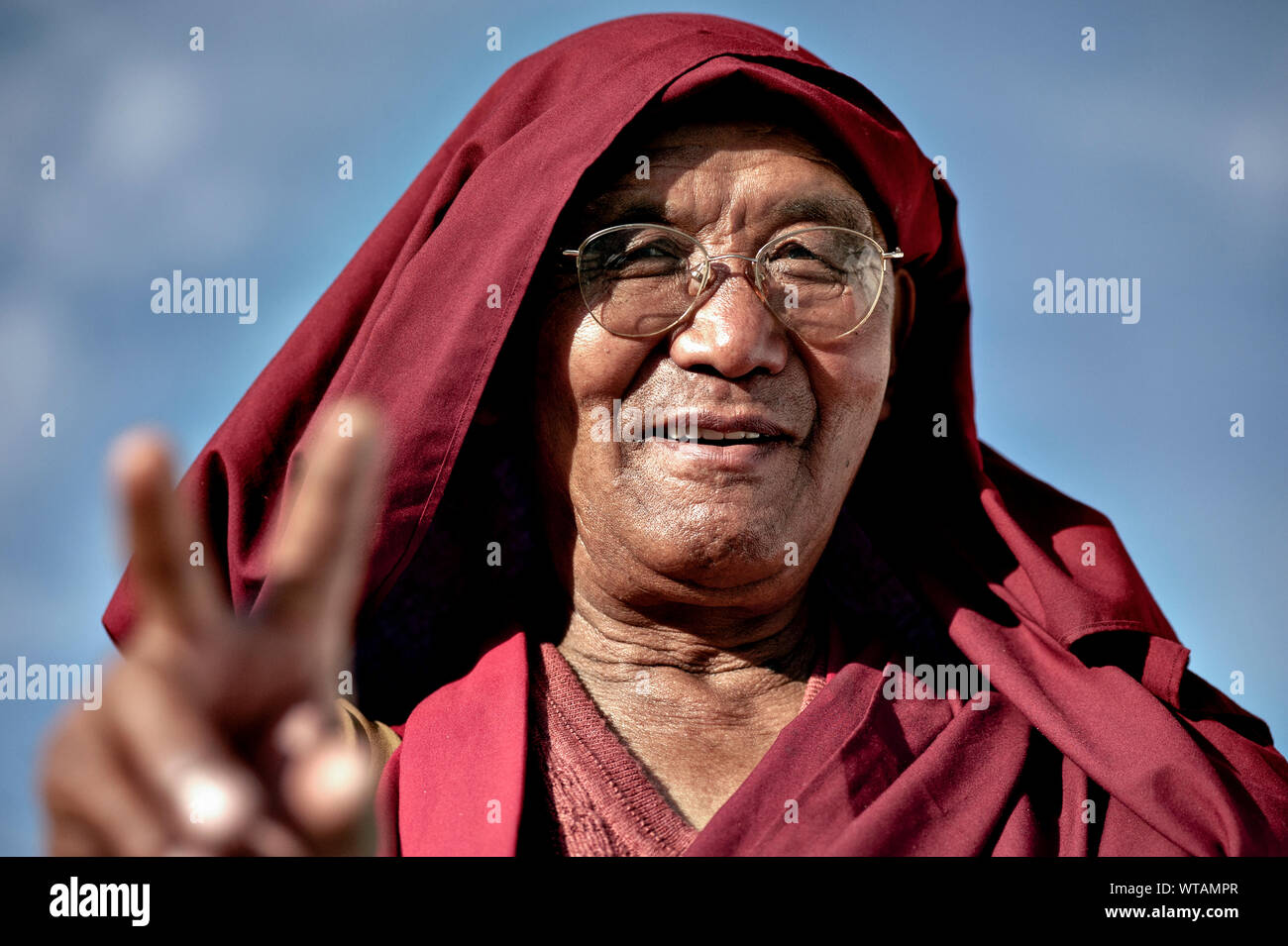 Monk making peace sign and smiling Stock Photo