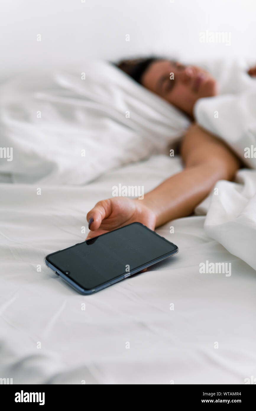 woman sleeping in bed phone in her hand Stock Photo Alamy