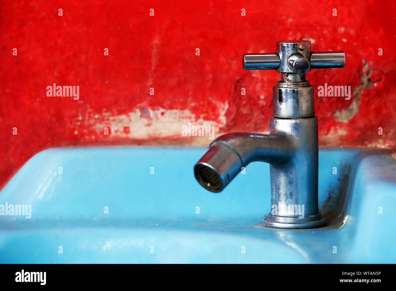 Close-up Of Faucet On Sink By Red Wall Stock Photo
