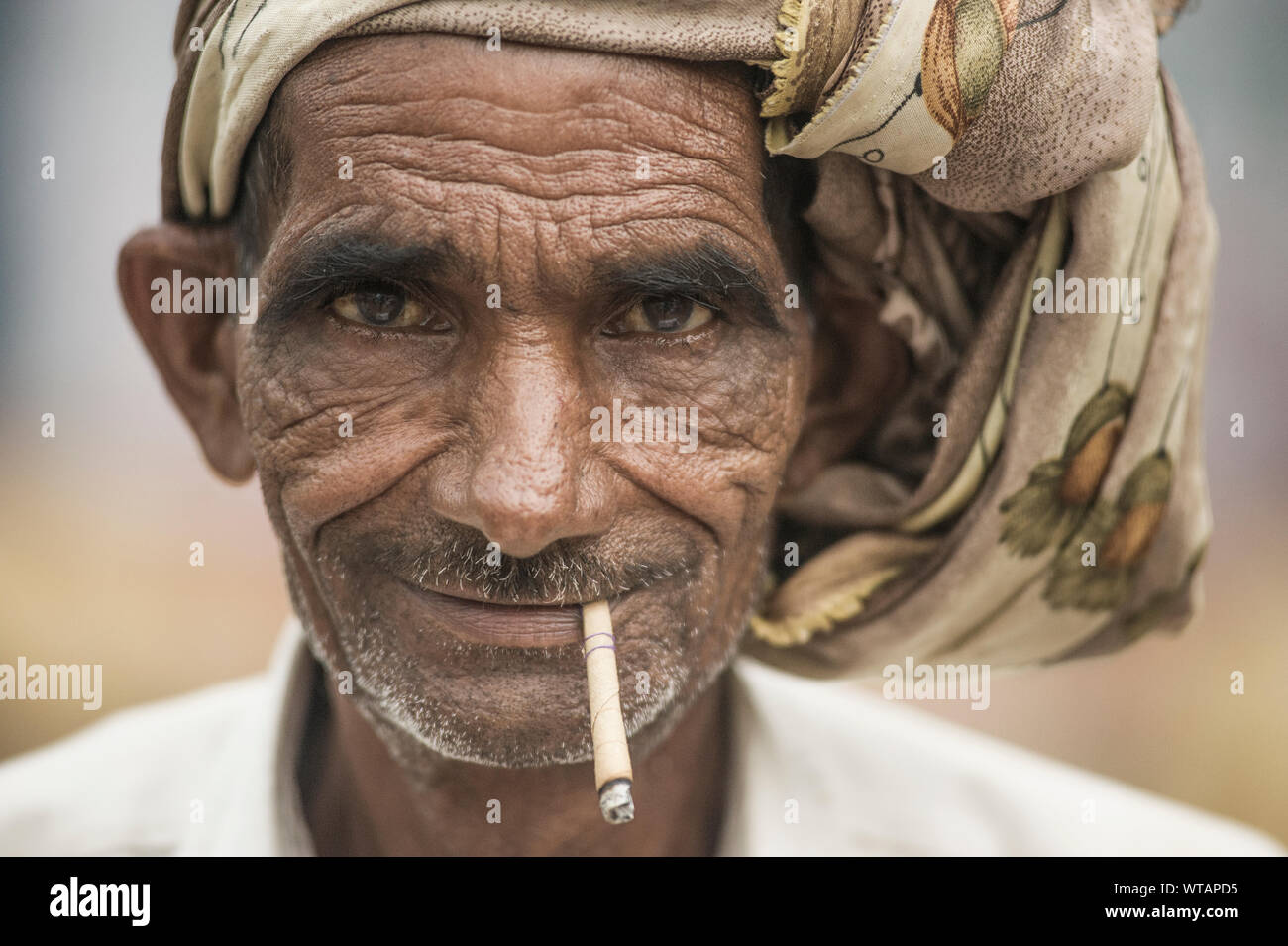 Old hindu man smoking straw cigarette Stock Photo
