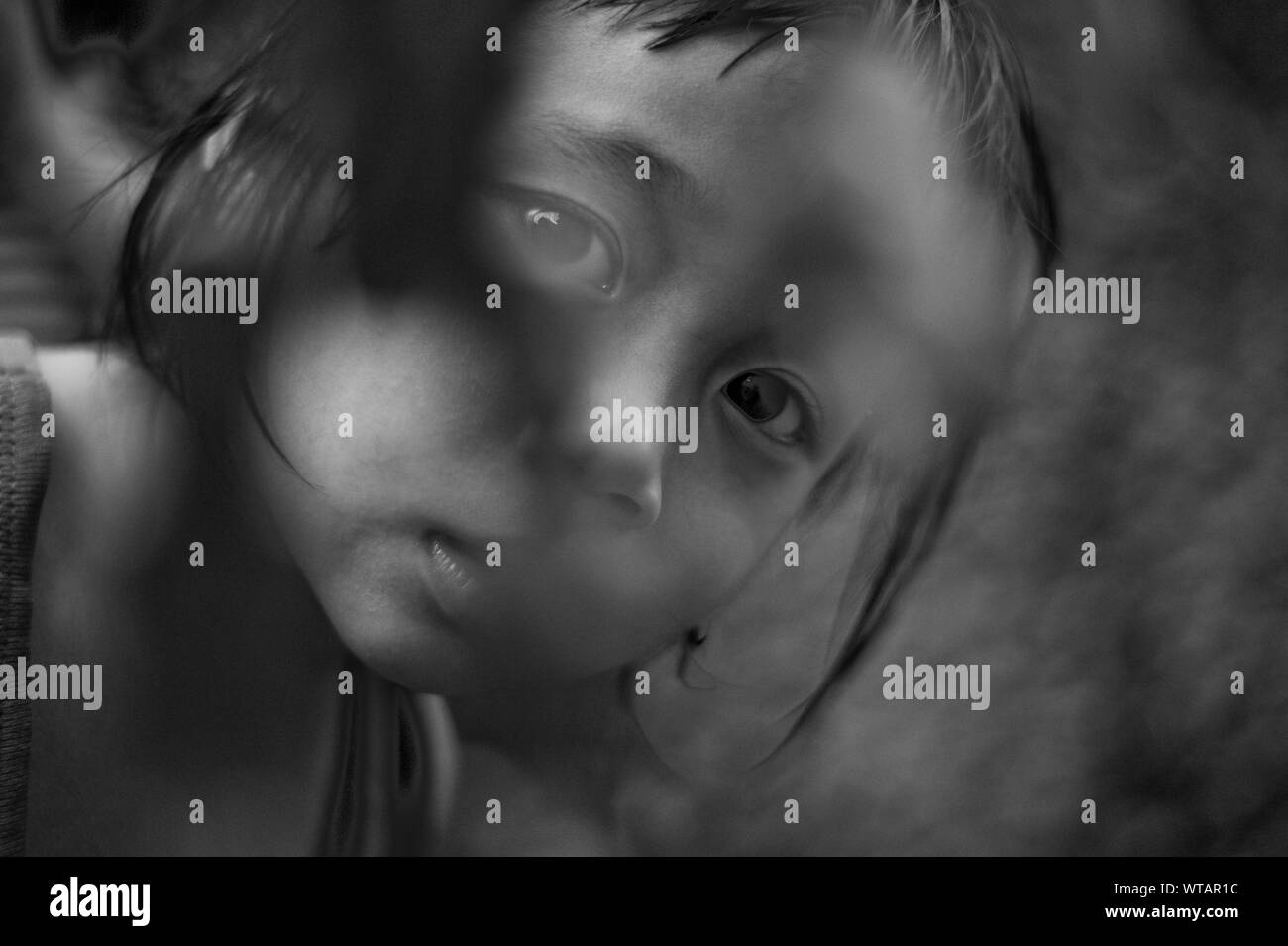Young Thai boy looking through bush foliage Stock Photo