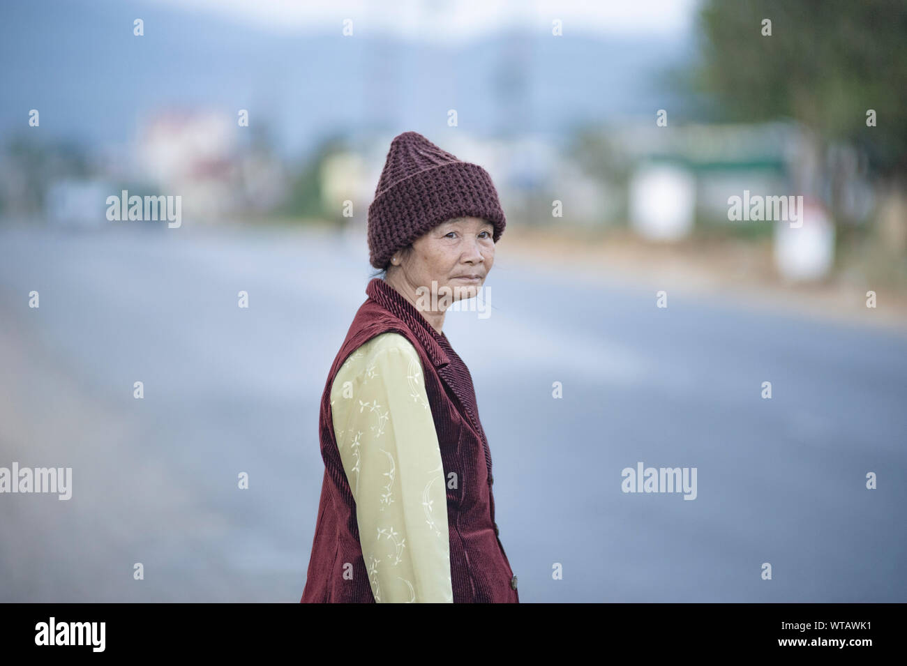 Old Vietnamese lady in the city outskirts Stock Photo