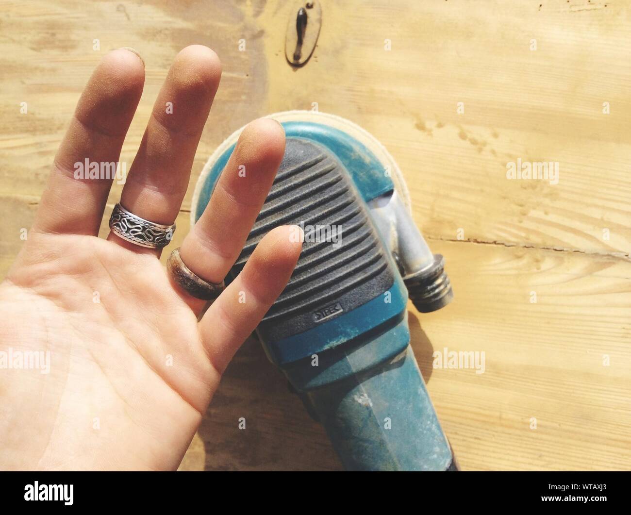 Man Showing His Hand With Sander On Wood Material Stock Photo
