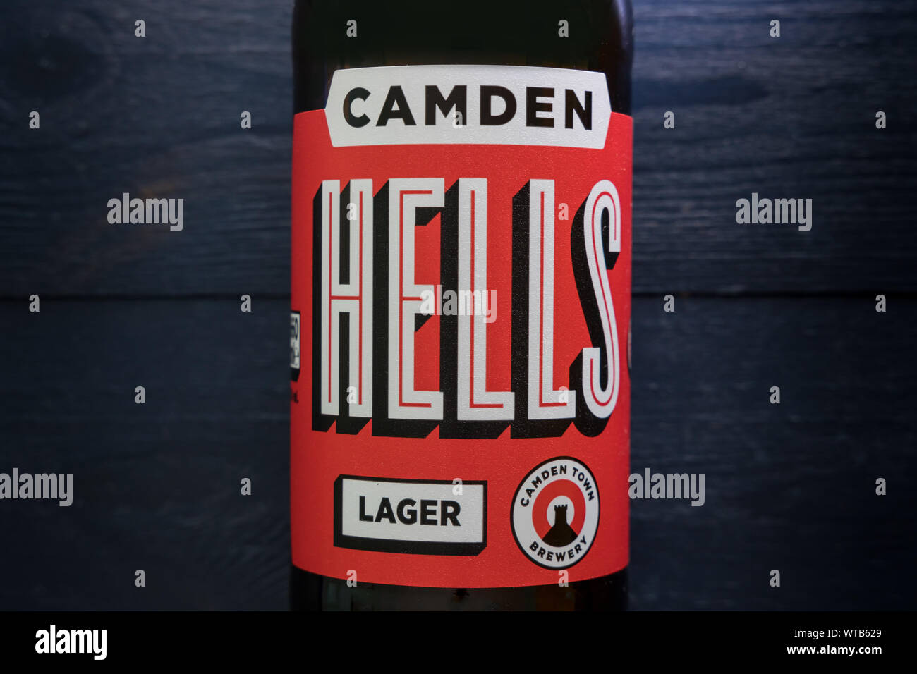 LONDON - SEPTEMBER 3, 2019: Camden Hells craft beer bottle on dark wood background Stock Photo