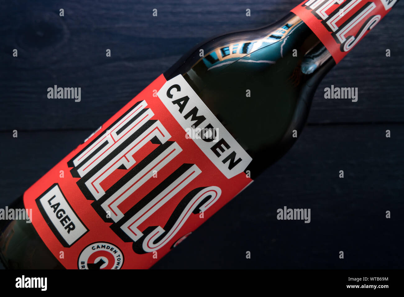 LONDON - SEPTEMBER 3, 2019: Camden Hells craft beer bottle on dark wood background Stock Photo