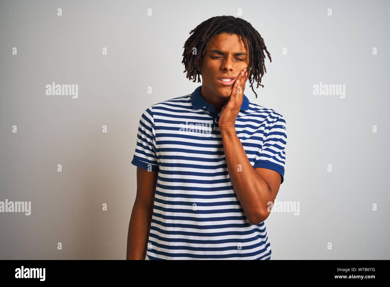 Afro man with dreadlocks wearing striped blue polo standing over ...