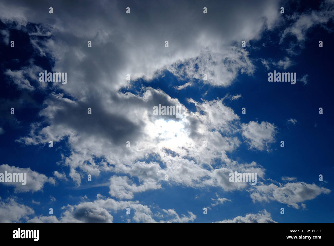 dramatic cloudy blue sky, sun behind clouds, norfolk, england Stock Photo