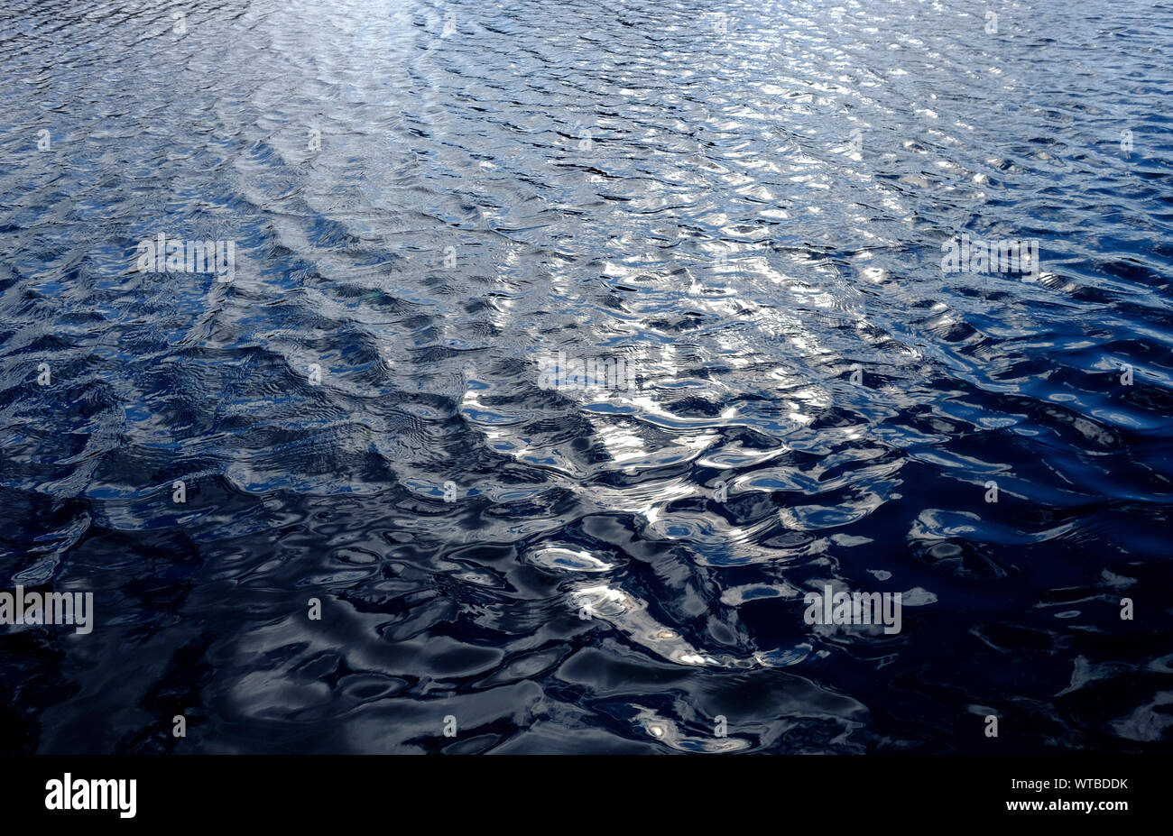 sunshine reflected on blue choppy water Stock Photo