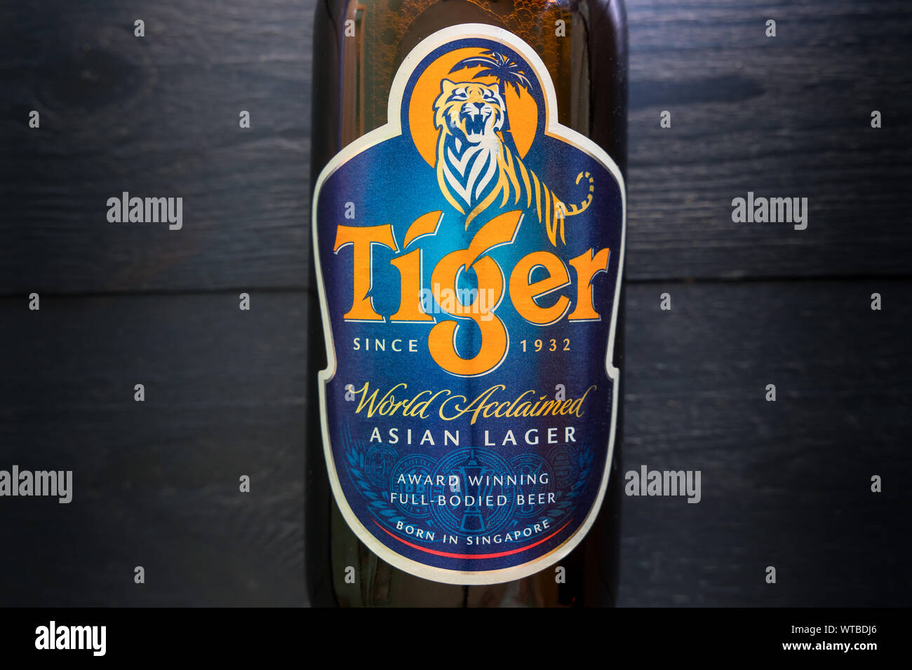 LONDON - SEPTEMBER 3, 2019: Tiger Asian lager beer bottle on dark wood background Stock Photo