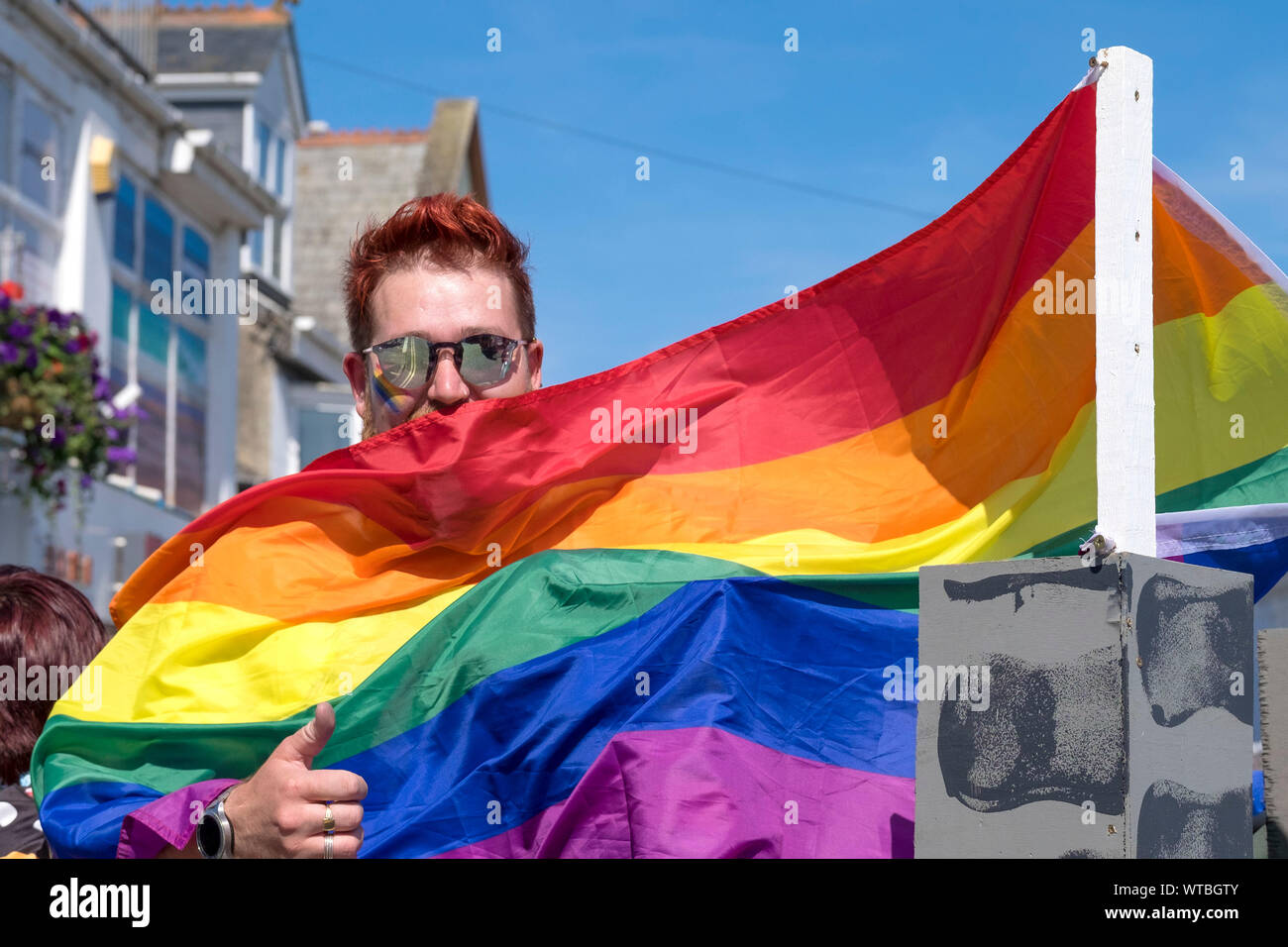 A man wrapped in a Gay Pride Rainbow flag participating in the Cornwall Pride Parade in Newquay in Cornwall. Stock Photo