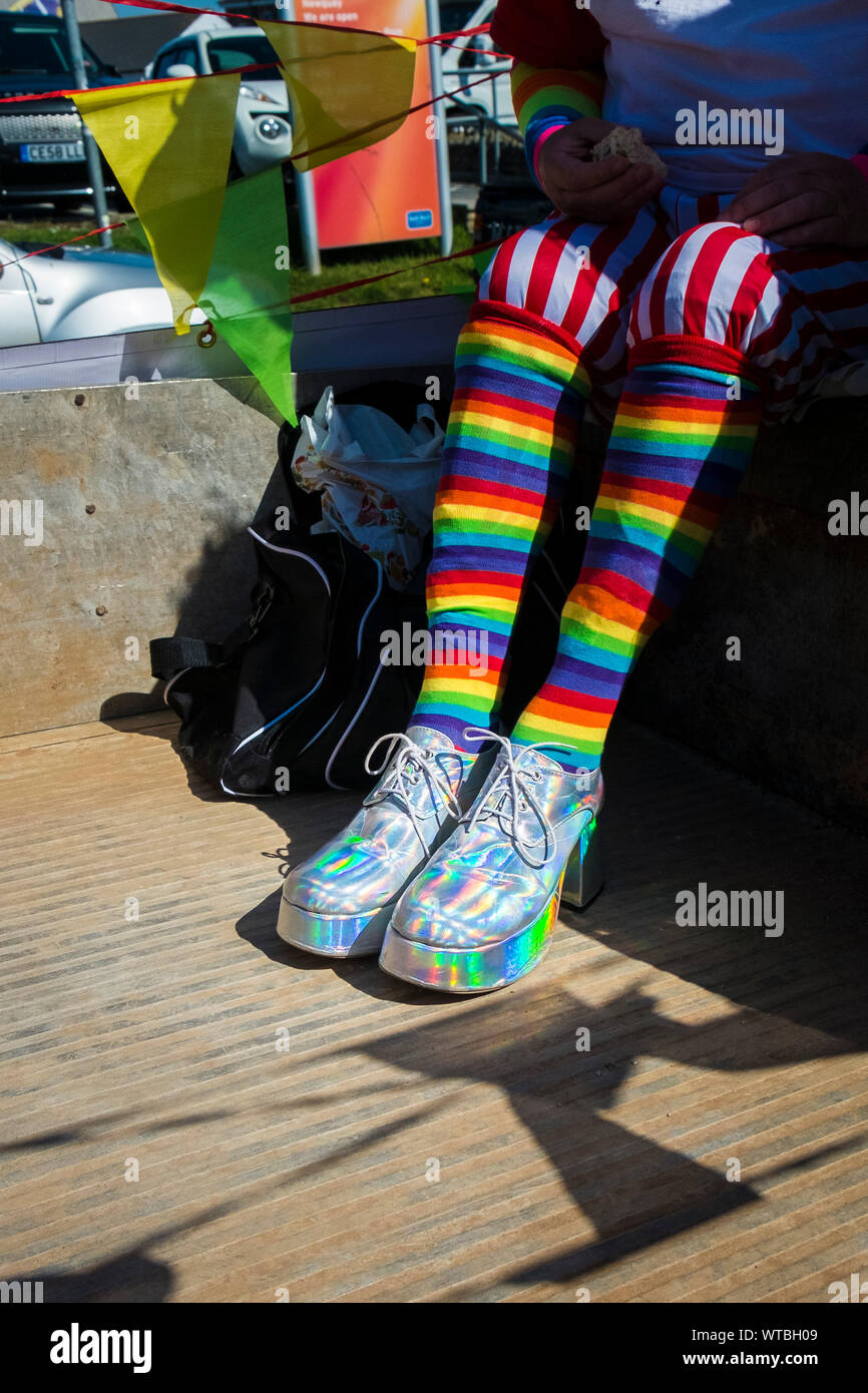 A man wearing brightly coloured knee length socks and iridescent platform shoes. Stock Photo