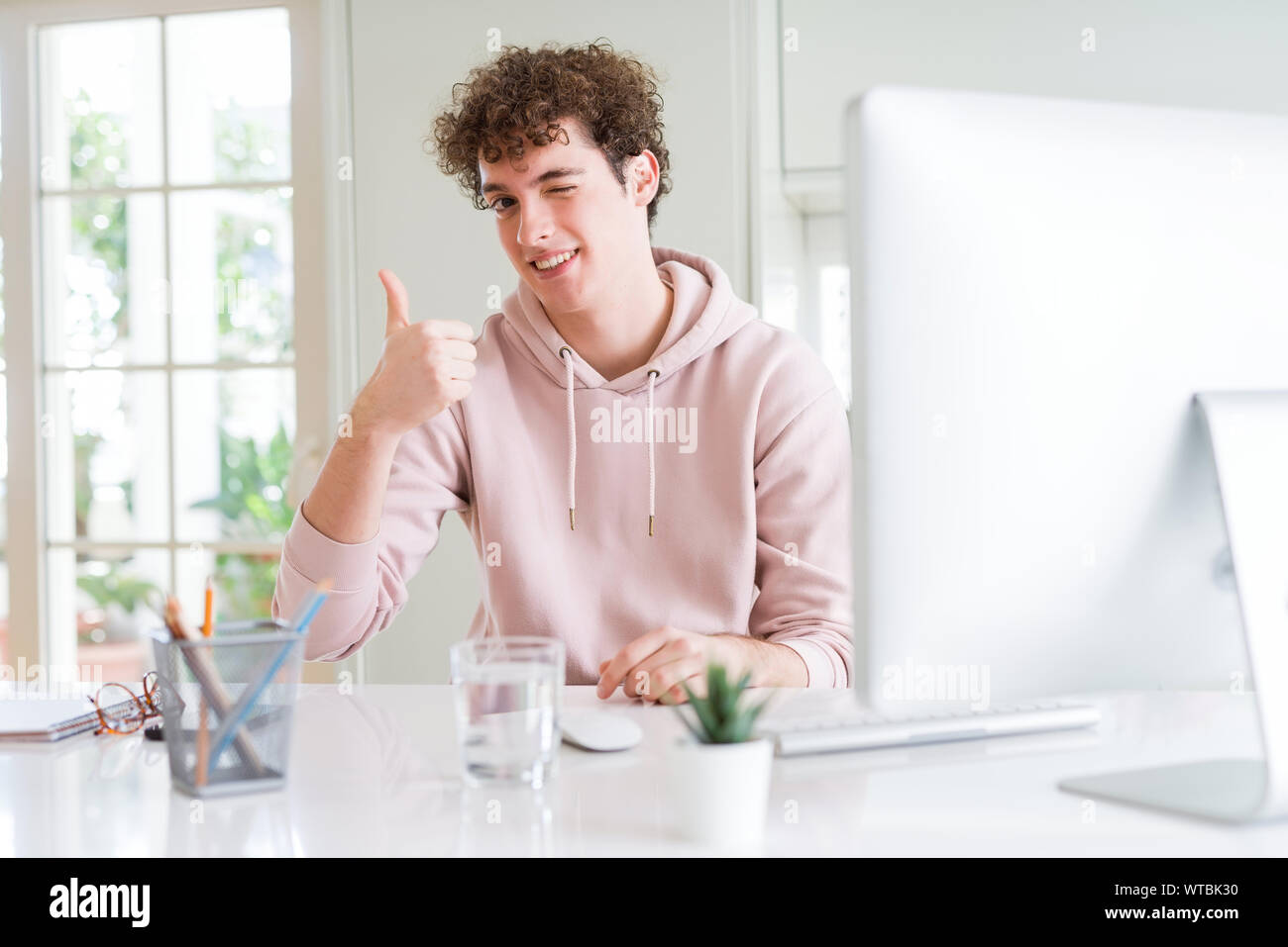 Young student man using computer happy with big smile doing ok sign ...