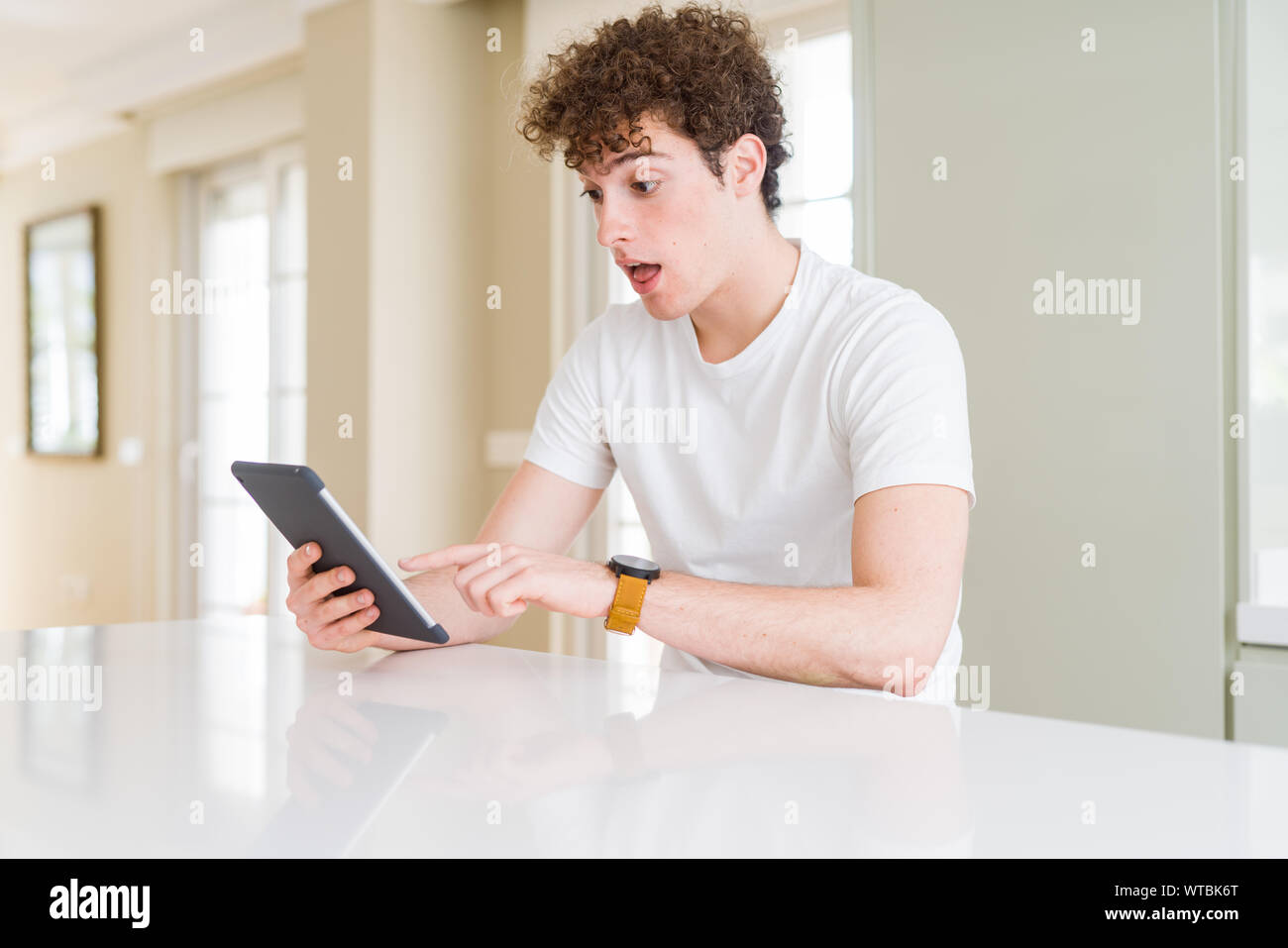 Young man using touchpad tablet scared in shock with a surprise face