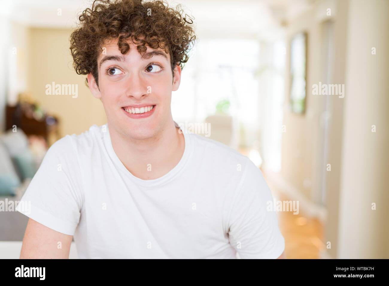 Young handsome man wearing white t-shirt smiling looking side and ...