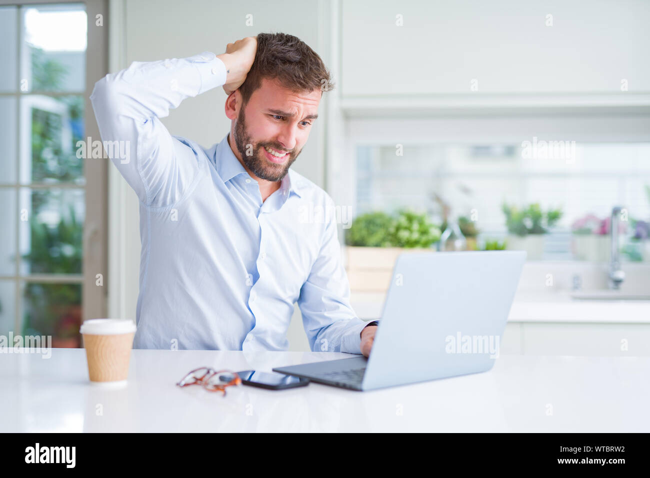 Handsome man working using computer laptop and drinking a cup of coffee ...