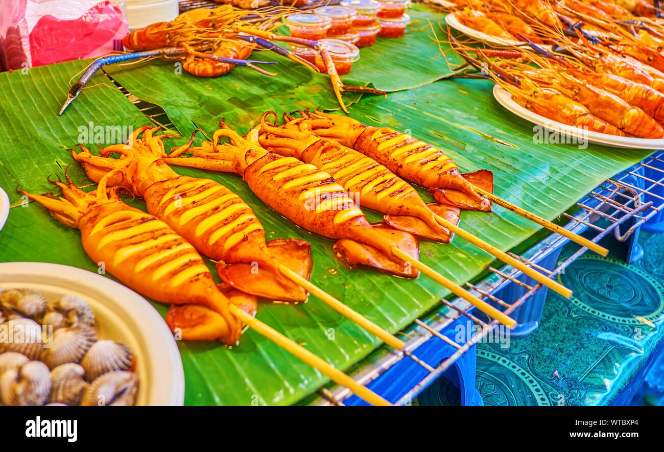 The grilled squids and other seafood on the showcase of the food market in Central World Plaza in the heart of business district in Bangkok, Thailand Stock Photo