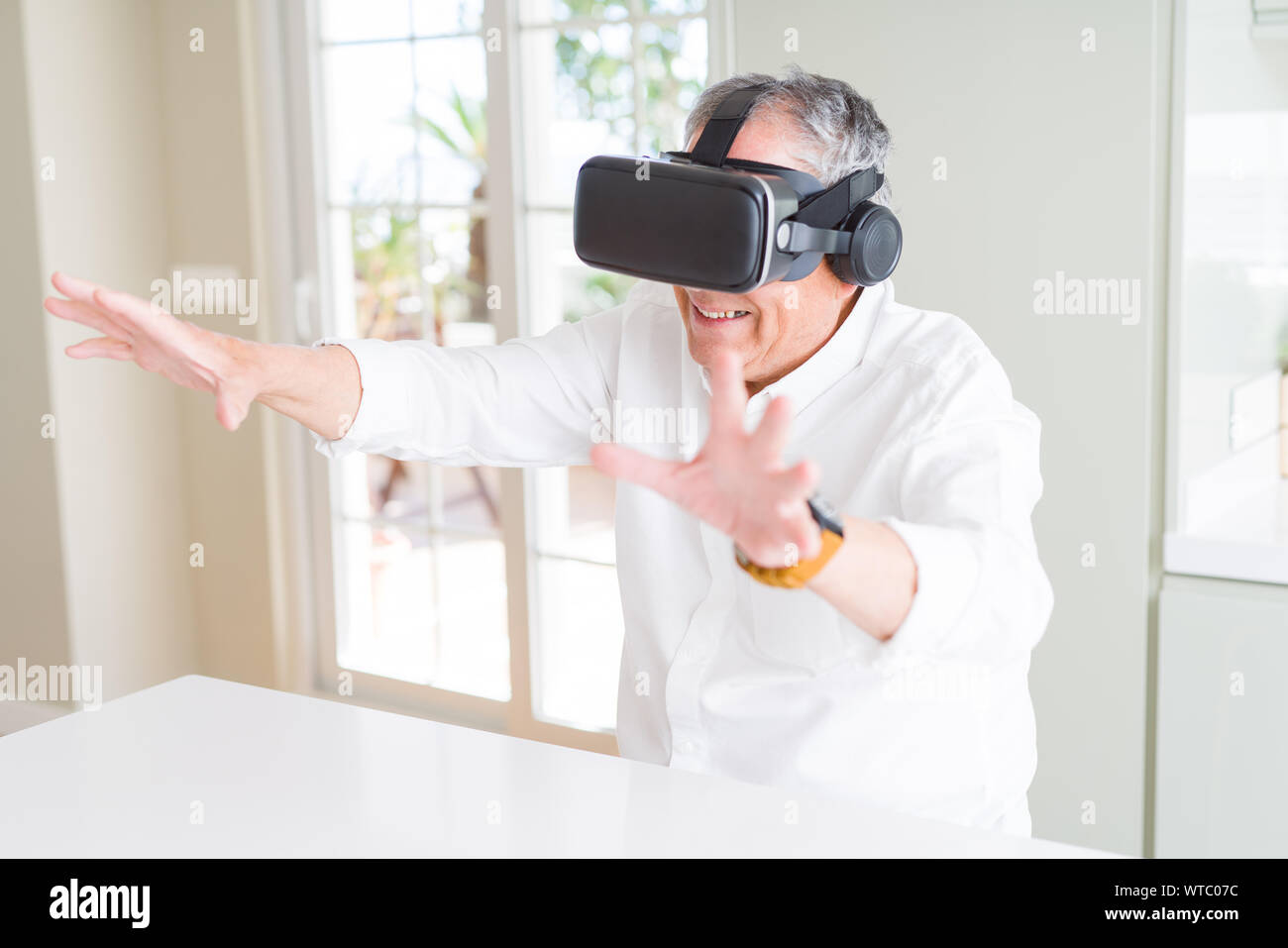 Man wearing virtual reality glasses smiling looking very happy and excited Stock Photo