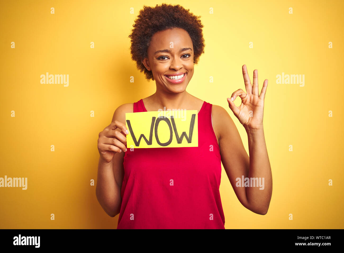 Young african american woman showing wow banner board over yellow ...