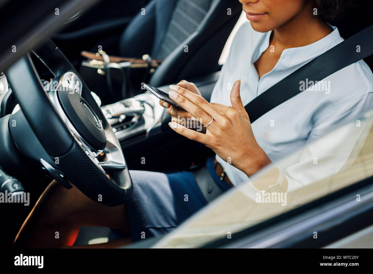 Unrecognizable woman using smartphone while sitting in car. Stock Photo