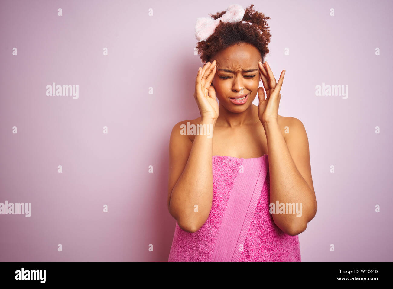 African american woman wearing shower towel after bath over pink