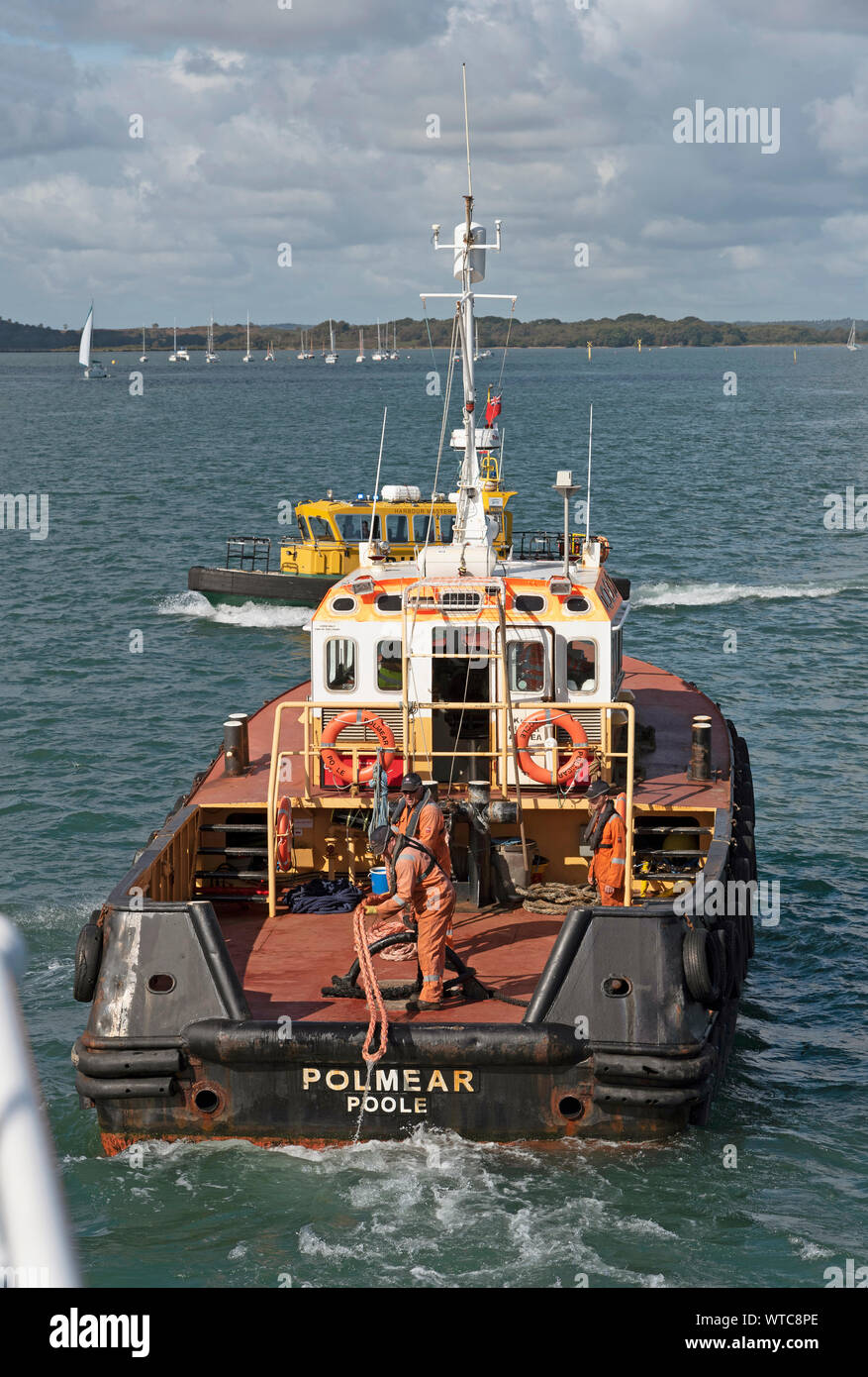 Poole Harbour, Dorset, England, UK. September 2019.  Tug crew pulling in line from a vessel they have just pulled from a berth. Stock Photo