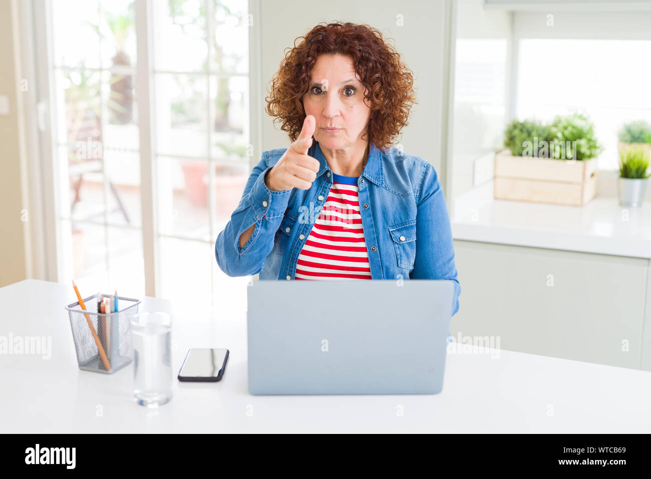 Senior woman working using computer laptop pointing with finger to the ...