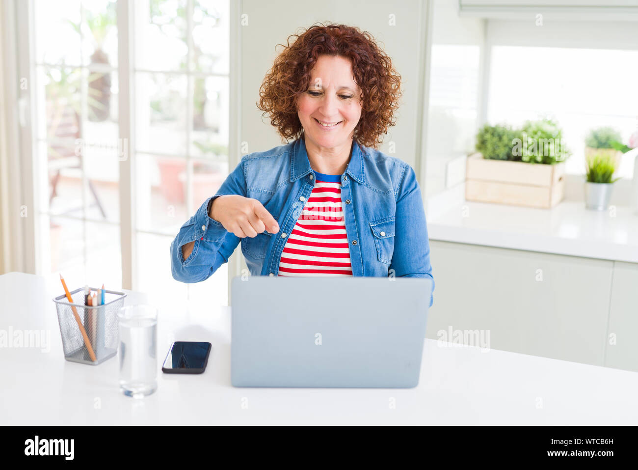 Senior woman working using computer laptop very happy pointing with ...