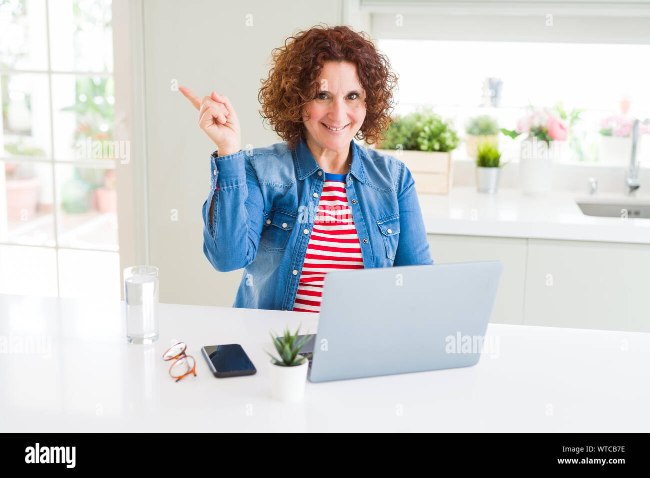 Senior woman working using computer laptop very happy pointing with ...