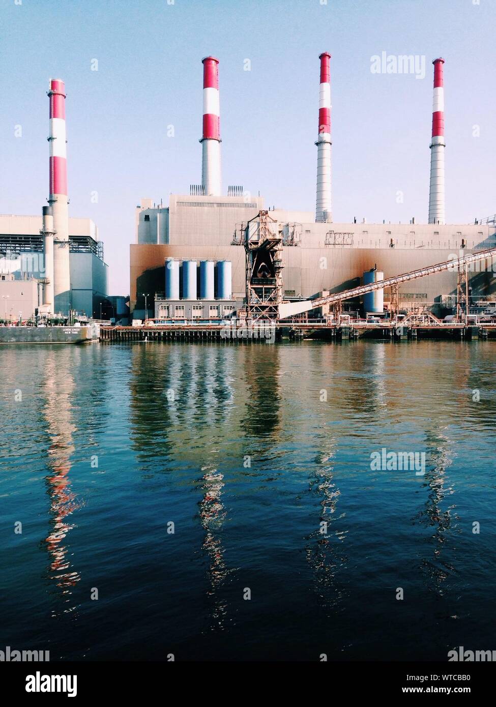 Exterior Of Factory With Smoke Stacks By River Stock Photo