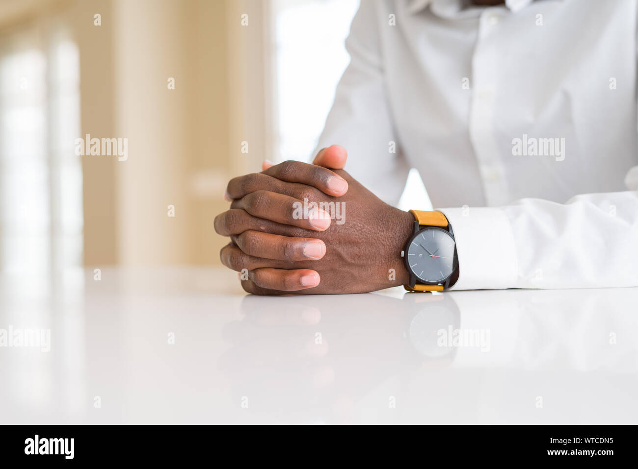 Close up of crossed hands of african man over table Stock Photo - Alamy