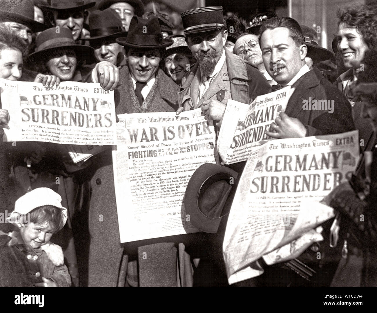 Jubilant Americans in Washington, D.C., show newspaper headlines which announce the surrender of Germany, ending World War I, November 8, 1918. Stock Photo