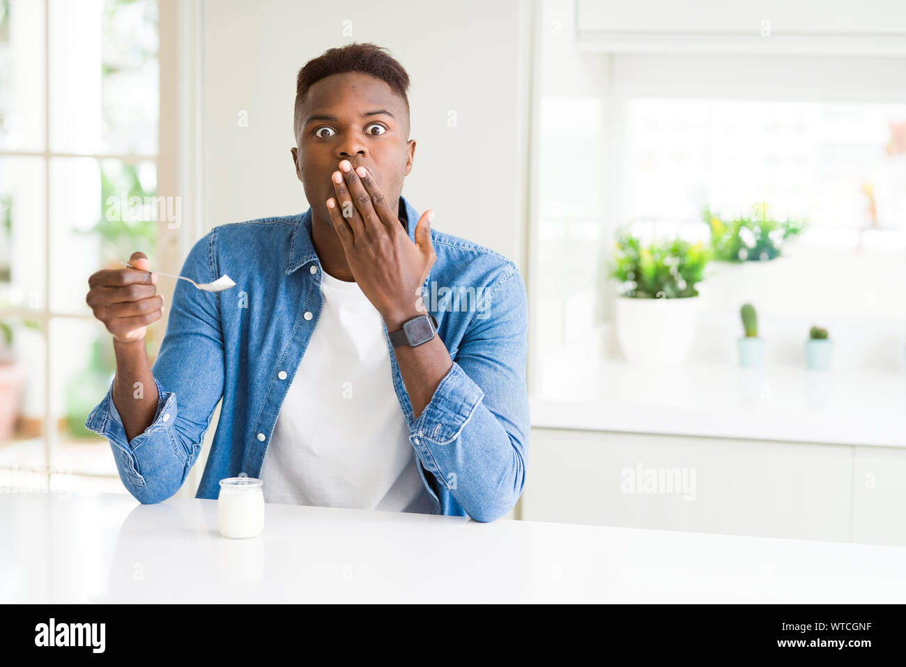African american man eating healthy natural yogurt with a spoon cover ...
