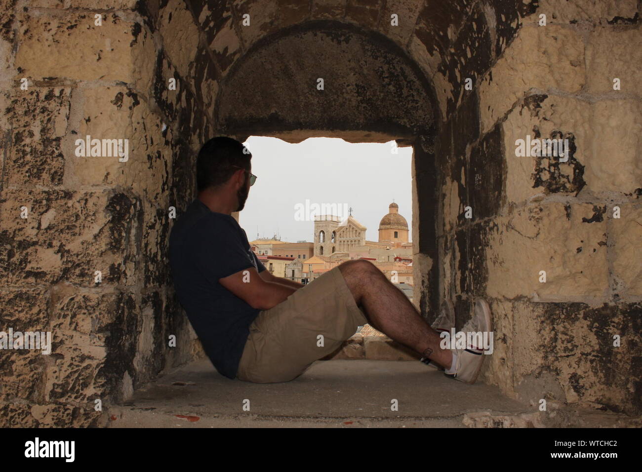 Man Sitting In Window At Torre (no Suggestions) Against Cagliari Cathedral Stock Photo