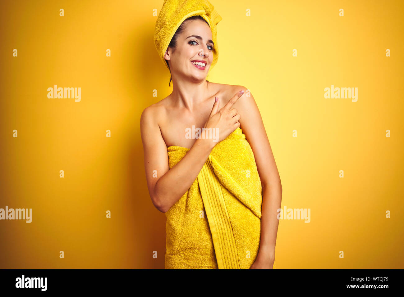 Beautiful woman wearing shower towel on body and head over yellow ...
