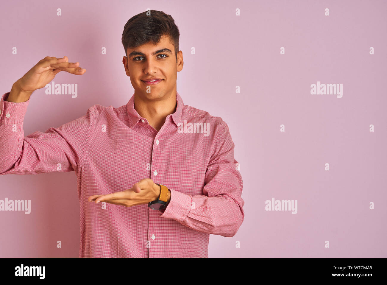 Young indian man wearing elegant shirt standing over isolated pink ...