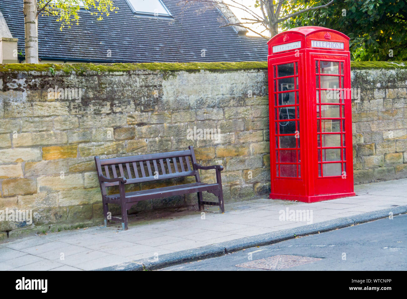A Red Telephone Box and Public Bench in a UK Street Stock Photo