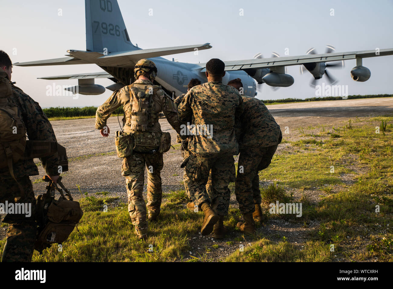 Marines with Echo Company, Battalion Landing Team, 2nd Battalion, 1st Marines, 31st Marine Expeditionary Unit, carry a simulated casualty to a KC-130 during a simulated airfield seizure after a long-range raid from the amphibious assault ship USS Wasp (LHD 1) at Ie Shima Training Facility, Okinawa, Japan, Aug. 13, 2019. The 31st MEU and Amphibious Squadron 11, aboard Wasp Amphibious Ready Group ships, conducted a series of sequential operations which simulated naval expeditionary combined-arms maneuver from amphibious assets to shore, utilizing Marine Air-Ground Task Force capabilities integra Stock Photo